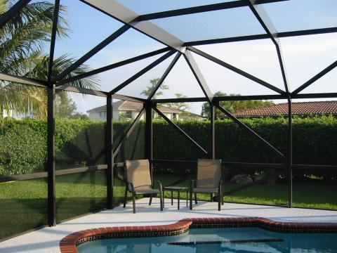 Contemporary Pool with trimmed bushes lining back yard
