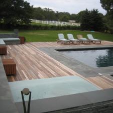 Contemporary Pool with wood and stone pool deck