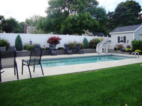Traditional Pool with plant and shrub border around fence