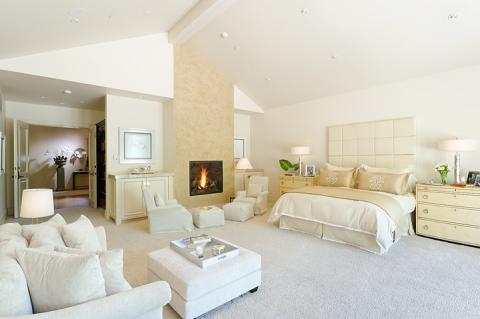 Transitional Bedroom with tall light tan stone fire place facing