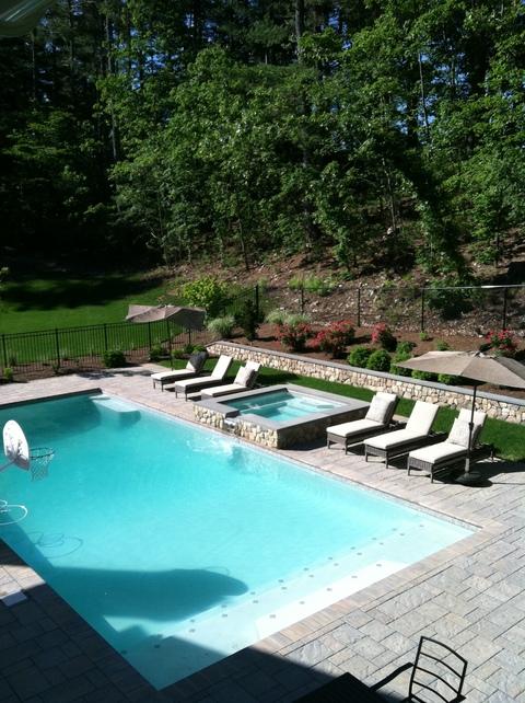 Contemporary Pool with raised hot tub with stone exterior