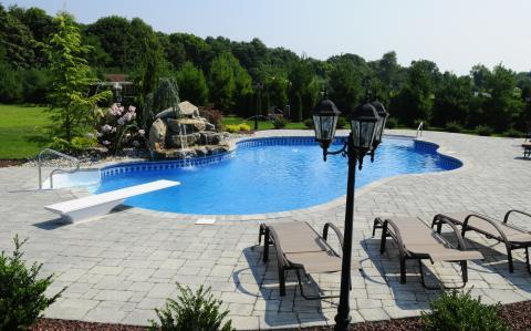 Traditional Pool with gray concrete brick pool deck