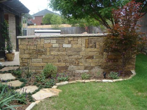 Transitional Landscape with stone brick lining flower bed