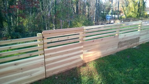 Modern Landscape with gate in a 6 foot horizontal slat and plank fence