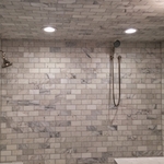 Large walk in shower with marble tile wall, multi-shower heads, and tiled shower niche