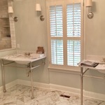Transitional bathroom with light marble flooring, double sink vanity, and white plantation shutters