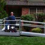 Man in powerchair using ramp to enter his home