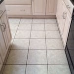 tan tile in kitchen with light cabinetry and black appliances