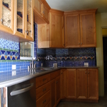 moroccan backsplash with medium stained cabinetry and solid surface counter