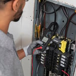 Electrical Tech looking at a breaker box