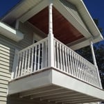 A two car garage with a room above with a walk out nook with vinyl railing