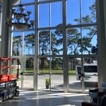 This image showcases a church foyer in Tampa, Florida, where Precision Safety Films has installed high-quality tinted window film. Designed to reduce heat and glare, the film ensures a cooler interior environment with controlled light intensity, while also enhancing privacy. The clear view of trees throgh the treated glass demonstrates the film's seamless integration with the building's aesthetic.