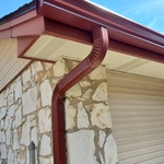Gutter should run to the end of your roof material, not just your fascia board. This will ensure you collect all rainwater and avoid annoying drips.