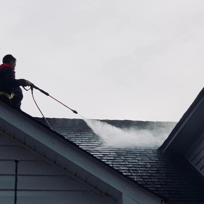 One of our employees on the roof preforming a roof wash.