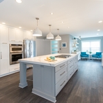 This beautiful kitchen was part of an entire first floor remodel, where this creative homeowner had a very specific style in mind: clean lines, light tones, and contemporary everything. This strong aesthetic was emboldened with an over-sized island, shaker cabinets, and statement fixtures. And, because no kitchen is complete without a coffee station, floating shelves and soft seating in the en suite cafe bring the space full circle. Design and Construction by Meridian.