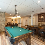 This Finished Basement in Hatfield, PA captures the homeowner’s vision of an in-home Irish pub. This expansive basement has many features designed specifically for the customer’s needs—including special lighted displays for his model trains, custom-depth drawers to store his extensive record collection, and an accessible bathroom. The stone fireplace and sports bar backsplash give this spacious basement just the right amount of rustic, cozy feel. Design and Construction by Meridian.