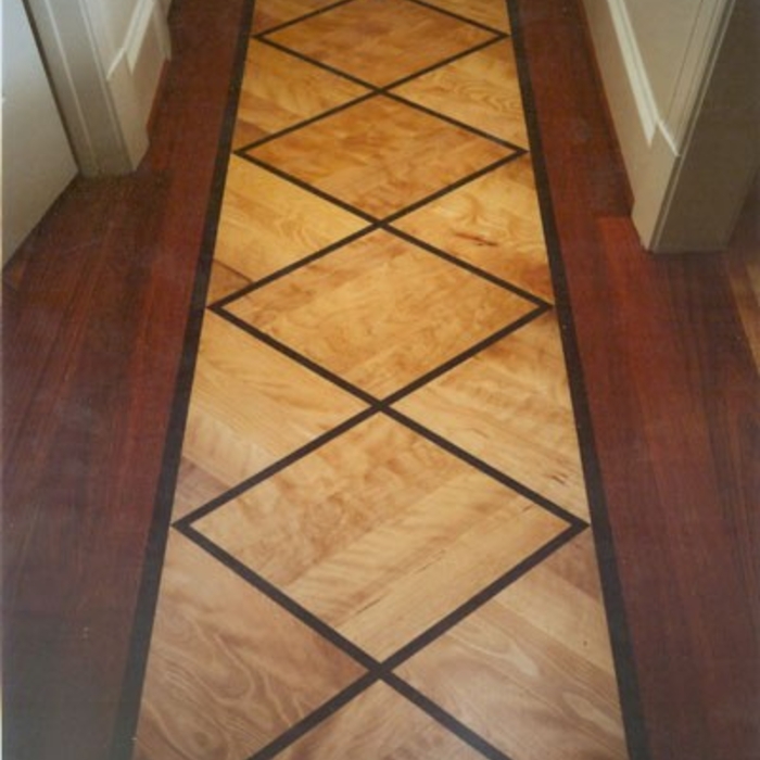 Hallway continuing the similar design from entry hall using diamond pattern with the light and dark hardwoods.