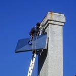 Technician bringing a new, custom stainless steel chase cover to replace a corroded "builder grade" galvanized steel chase cover.