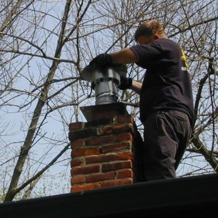 Installing a chimney cap at the top of a relined central heater flue.
