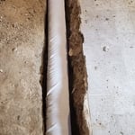 Installation of Socked Drain Tile on top of Stone around perimeter of Basement