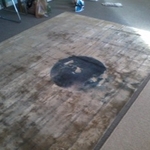 Silk rug with large 3' diameter furniture dye stain in center before cleaning