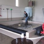 Owner Trent Keast is hand cleaning a rug in the submersion pool at Premier Rug Spa.