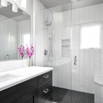 White marbled quartz countertop over black panel vanity and new subway tile shower with black hex tile floor