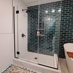 Picture shows new bathroom featuring shower w/ custom shower base, niche, wall tile, shower doors and slipper tub.
