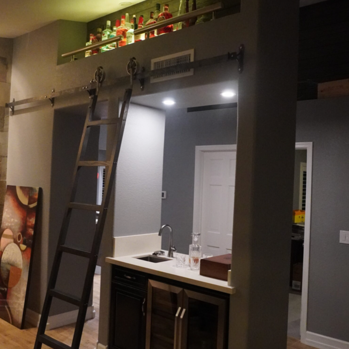 Custom wet bar with lighting and a librarian ladder.