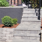 Front step built with Chatau wall block from Western Interlock and pavers in the Rio color from Belgard With Black Alum. basic railing.