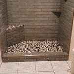 green wall tile and stone shower floor