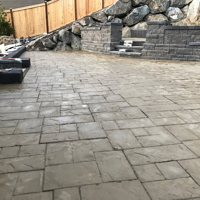 Colored, Stamped Concrete Patio with Concrete Block Retaining Wall and Stairs leading to a smaller patio.