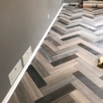 Herringbone pattern tile floor with quarter round molding.