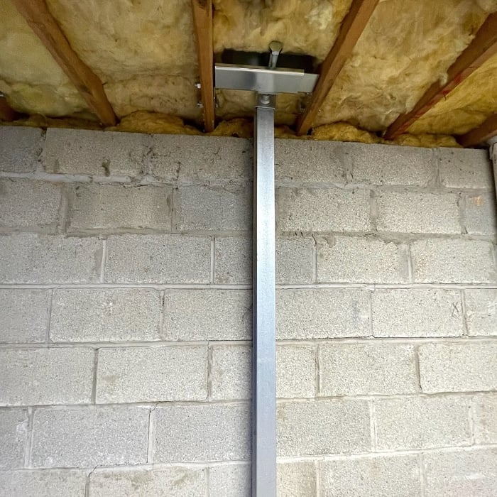 The wall height is measured to cut PowerBrace beam to its length and the bottom of the beam is anchored to the floor. The top bracket is installed and the beam is secured. This patented design can be straightened over time, eliminating future bowing, buckling, or inward tilting movements.