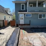 The deck and concrete are removed. The area of the patio is dugout to approximately 1ft. Geotextile fabric is laid over the area and topped with 8-10in. Of 411 limestone base compacted every 2inches. The area is screeded level using #9 limestone and pavers begin to be laid.
