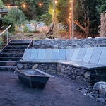 Fire pit area at dusk. Stone bench serves dual functions as a lounge and as a retaining wall.