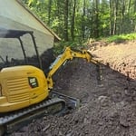 Excavator using hydraulic hammer to break out shale for pad placement.