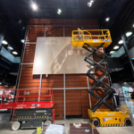 Vegas-Moving team operating a scissor lift and installing a 5-story tall tarp.