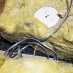 We see dirt in the insulation and when we pull back the fiberglass insulation we can see the attic was not air sealed.