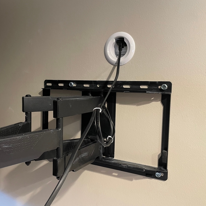 Installed concealed wire kit for top hole. TV power cable plugged into the electrical outlet of the kit. Kit has finished plate on it.