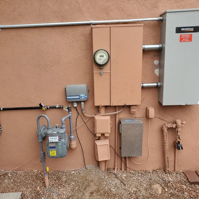 Automatic transfer switch with conduit pipe leading wires and gas between panels and generator.