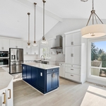 This Sammamish kitchen remodel blends timeless design with modern functionality. Featuring crisp white shaker cabinets, a bold navy island, quartz countertops, and brushed brass hardware, the space feels both elegant and welcoming. Thoughtfully chosen elements like a farmhouse sink, double ovens, and glass pendant lights create a bright, functional layout perfect for everyday living and entertaining. Natural light and open sightlines make this kitchen a true centerpiece of the home.