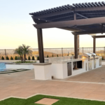 Complete backyard installation with a new pool, outdoor kitchen, seating walls, pavers, and artificial turf