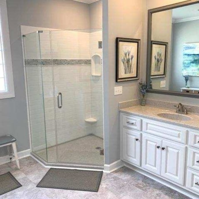 Large corner shower using our Onyx solid surface shower with tile inlay, built-in shelving, and a foot rest.
