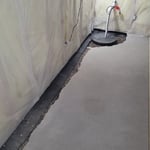 Our team created a trench to the footings and filled it with a drain pipe and rock to channel the water to the sump pump.