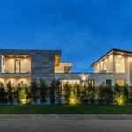 Side exterior of the home showing the custom stone tile siding and exterior lighting.