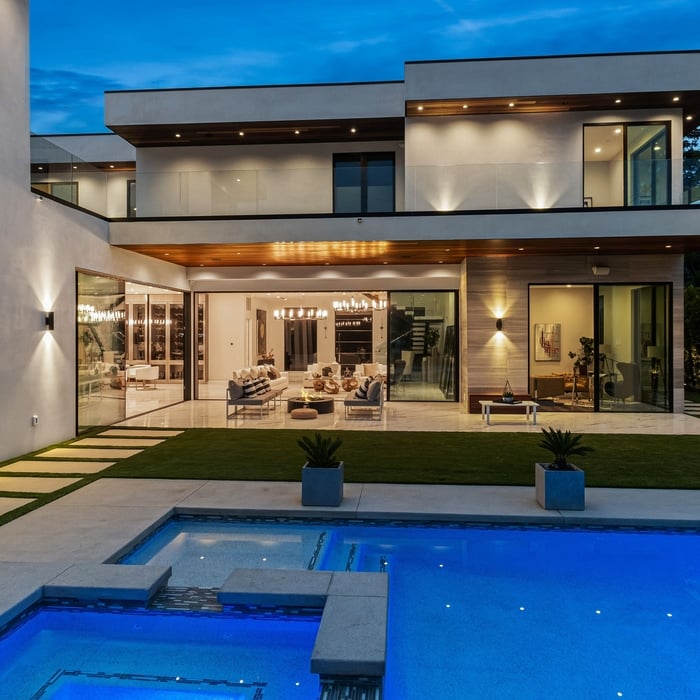 A shot of the backyard at night with the swimming pool in the foreground and the house behind it