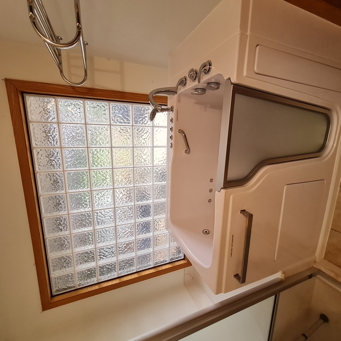 Walk-in tub with back wall shelf.