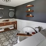 Wooden double vanity with matching floating shelves and picture-frame wainscoting.