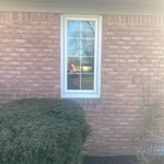 A narrow vertical window with white framing, perfectly complementing the home’s brick exterior. Surrounded by sculpted shrubs and decorative landscaping, this window adds a sleek, modern touch while maintaining a timeless aesthetic.